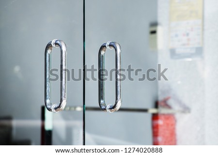 Metal door handle. Door handle on the glass door. Glass doors. Style. Modern interior. Entrance. Office. Office building.