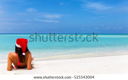 Girl with Christmas hat and bikini lying on tropical beach