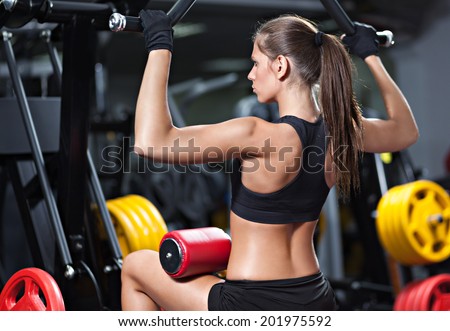 Attractive young woman working out on weight-lifting training machine