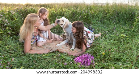 Happy family with dog. Mother with two children and dog playing on green meadow