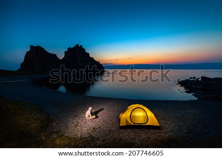 Tent near lake shore. Tourist at the camping close to lake at colorful sunset
