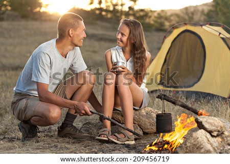 Young couple in camping and looking each other while water is boiling