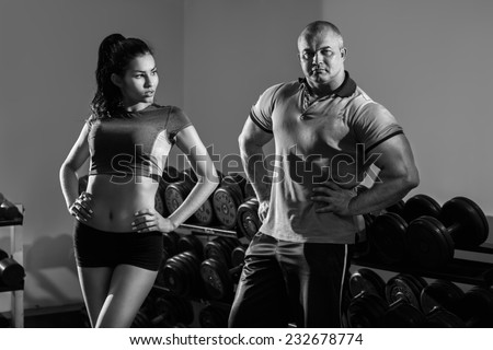 Young sportive woman with her trainer in the gym. B&W image