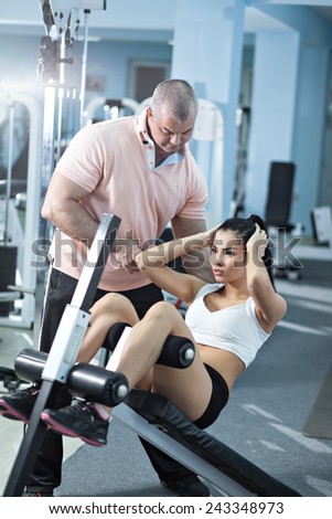 Woman at the health club with her personal trainer, learning the correct form