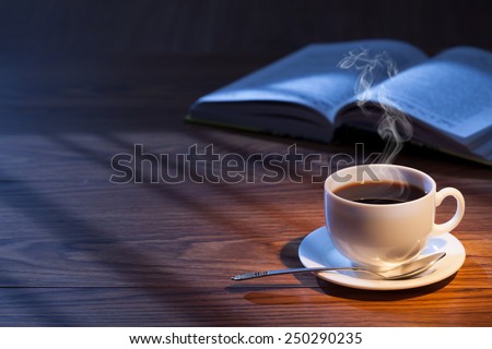 Cup of coffee, book and glasses on a wooden surface