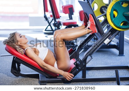 Sportive blonde using weights machine for legs at the gym