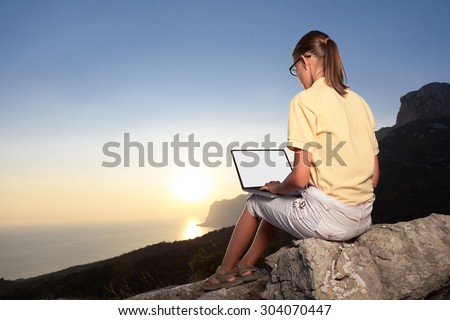 Young woman working with laptop on mountain peak