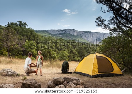 Father with son in the summer camping on a meadow