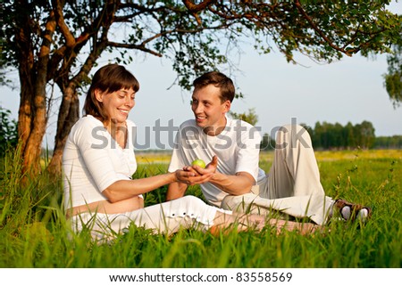 cheerful young couple on  green lawn. pregnant woman. grass blurred in foreground and background. XXXl