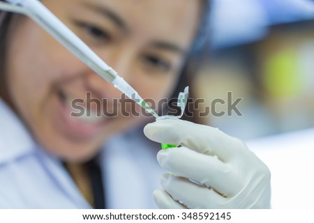 Scientist with pipette and test tube, examining samples and liquid in laboratory