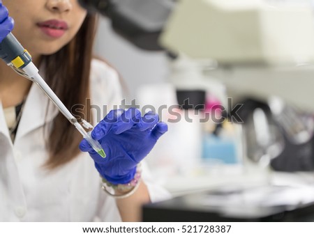 Scientist with pipette and test tube, examining samples and liquid in laboratory