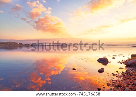 Breathtaking sunrise seascape scenery over Northern sea in Sweden. Epic dawn sea landscape. Lilac and red yellow colors scene. X letter guessed in shape form factor of cloud.