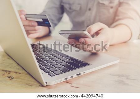 Online payment,Man\'s hands holding a credit card and using smart phone for online shopping with vintage filter effect