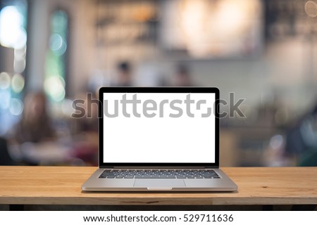 Laptop with blank screen on table. coffee shop blurred background.