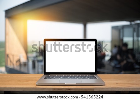 Laptop with blank screen on table of a cafe.
