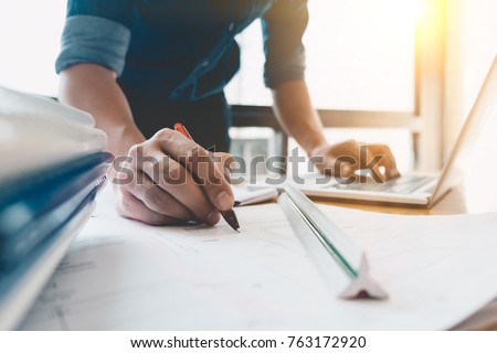 Image of engineer drawing a blue print design building or house, An engineer workplace with blueprints, pencil, protractor and safety helmet, Industry concept