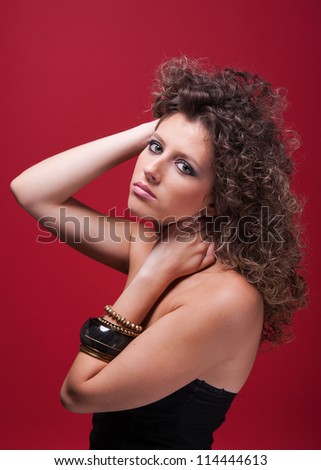young and beautiful woman, with curly hair, on purple background, side view, studio shot