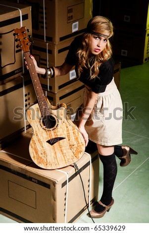 beautiful young woman with a classical guitar in a warehouse with boxes like scenario