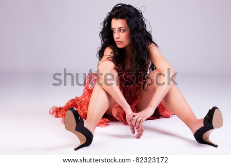 sad beautiful woman with elegant dress, on floor, studio shot