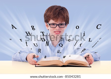 cute boy reading a book on his desk, with flying letters, isolated on blue, studio shot