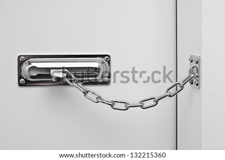the white door is closed on a silvery chain