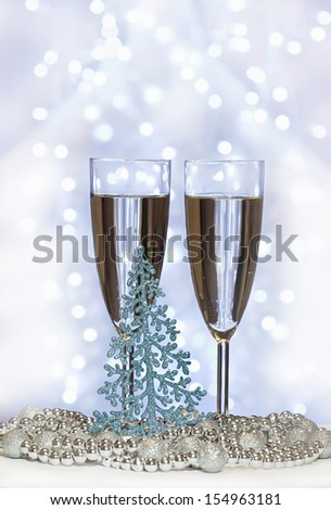 christmas toys, wine glasses and New Year\'s fir-tree against Christmas lights