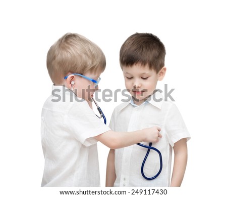 Four-year-old twins boys, in white linen shirts, one through a stethoscope listens to heartbeat of another, isolated on the white