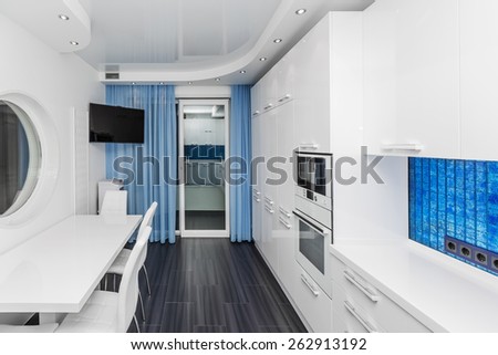 Specious modern white blue interior kitchen-dining room with the built-in household appliances and the TV