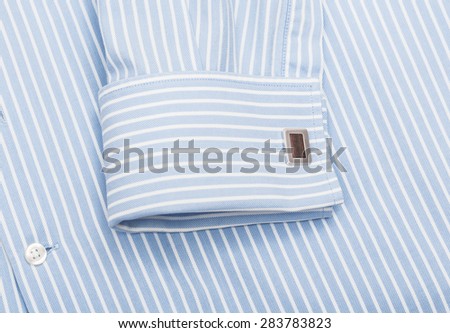 Sleeve of a striped blue shirt with a cuff link isolated on white background