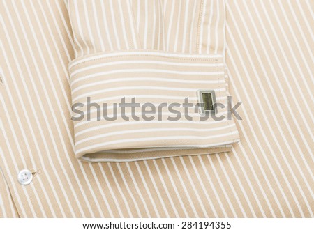 Sleeve of a striped yellow shirt with a cuff link isolated on white background