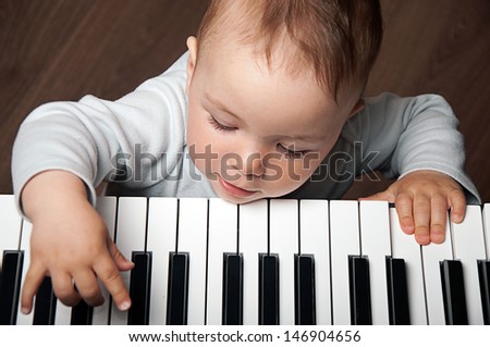 Little Baby Child Play Music On Black And White Piano Keyboard