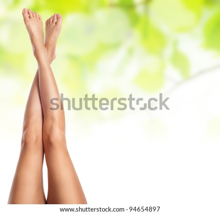 healthy sexy slender female legs over green natural spring background - spa and healthcare concept
