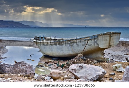Old fishing boat on marine beach after storm, Eilat, Israel