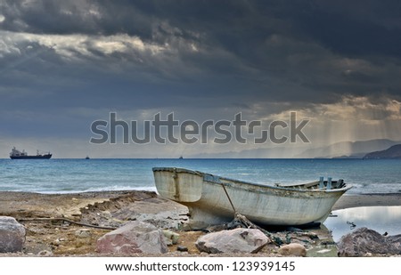 Old fishing boat on marine beach after tropical storm