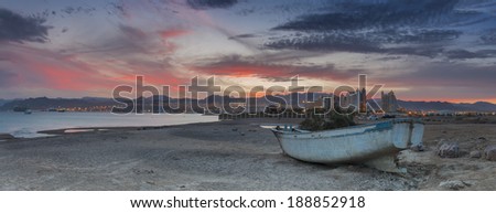 Sunset on a wild beach of the Red Sea with old fishing boat, Eilat, Israel