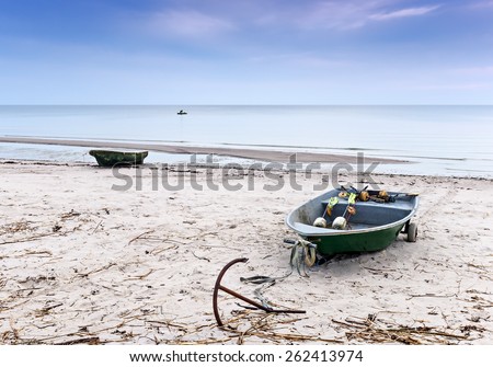 Coastal landscape with small fishing boats on sandy beach and lonely fisherman at horizon, Baltic Sea, Latvia, Europe