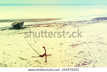 Anchored fishing boat on sandy beach of the Baltic Sea. Image toned in vintage warm colors style