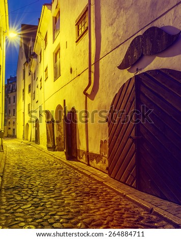 Narrow street in old city of Riga at night. Image toned in vintage warm colors for inspiration of retro style effect