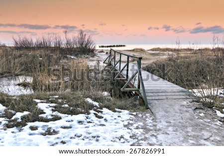 Coastal wintry landscape with wooden pedestrian bridge and old broken pier, Baltic Sea, Latvia, Europe