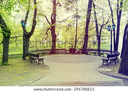Small square and garden benches in central park of riga city by springtime, Latvia. Image slightly toned for inspiration of retro style