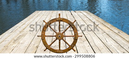 Composite image with old boat steering wheel and wooden pier above surface of water. May be used for different ideas and concepts