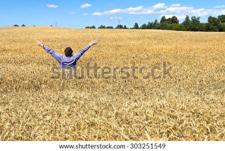 Man in the middle of wheat field. Useful for ideas and concepts of agriculture productivity and healthy food