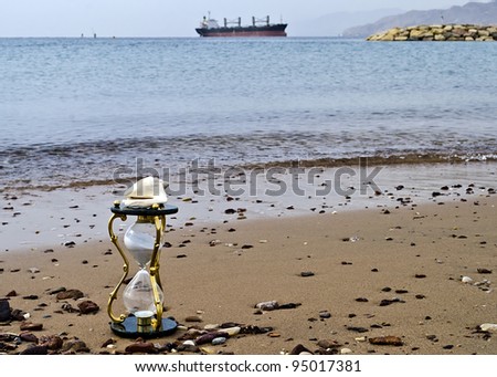Hourglass with a white shell on marine beach symbolizing vulnerability ecology system of the Red Sea