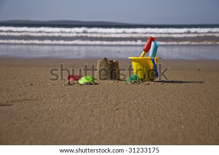 children\'s sand bucket and toys on scenic sunny beach with waves