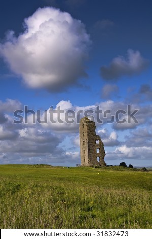 old irish castle ruins in green field with blue sky