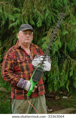 senior male cutting back tree branches in garden with chainsaw