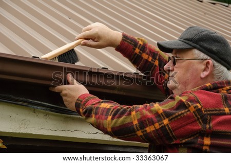 senior male cleaning out the shed gutter with brush