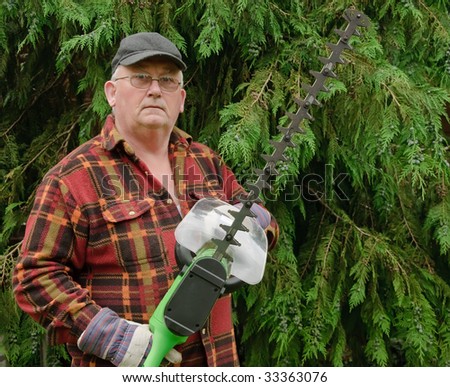 senior male cutting back tree branches in garden