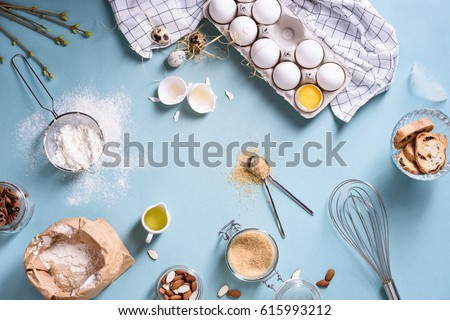 Bakery ingredients - flour, eggs, butter, sugar, yolk, almond nuts on blue table. Sweet pastry baking concept. Flat lay, copy space, top view.