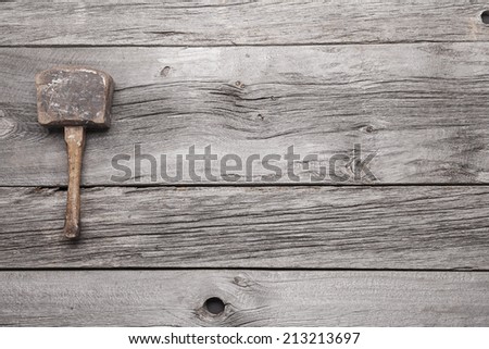 An antique wooden mallet on a background of grey barn board with lots of room for your copy.